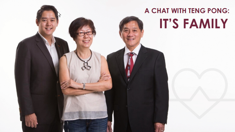Three people are standing and smiling at the camera. The text reads "A Chat with Teng Pong: It's Family" on the right side of the image. A faint heart graphic is visible in the background, emphasizing a warm family connection.