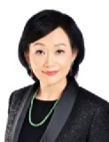 A woman with short black hair, wearing a black top, a black jacket, and a green beaded necklace, is smiling slightly, embodying the confidence and sophistication often seen in high net worth individuals.