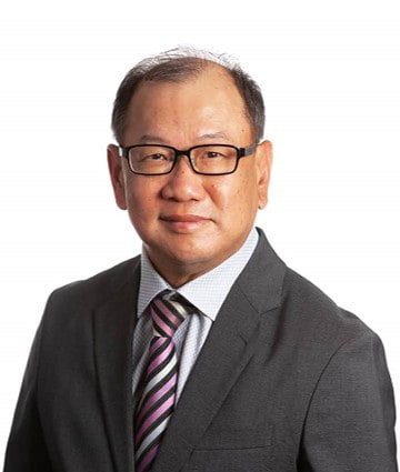 A man in a suit and tie with glasses poses for a professional headshot against a white background, ready to offer his expertise in estate planning courses Singapore.