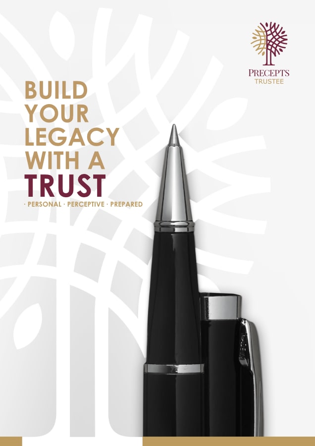 A close-up of a black and silver pen with text reading "Build Your Legacy with a Trust" next to it. The image also includes the Precepts Trustee logo and the words "Personal, Perceptive, Prepared.