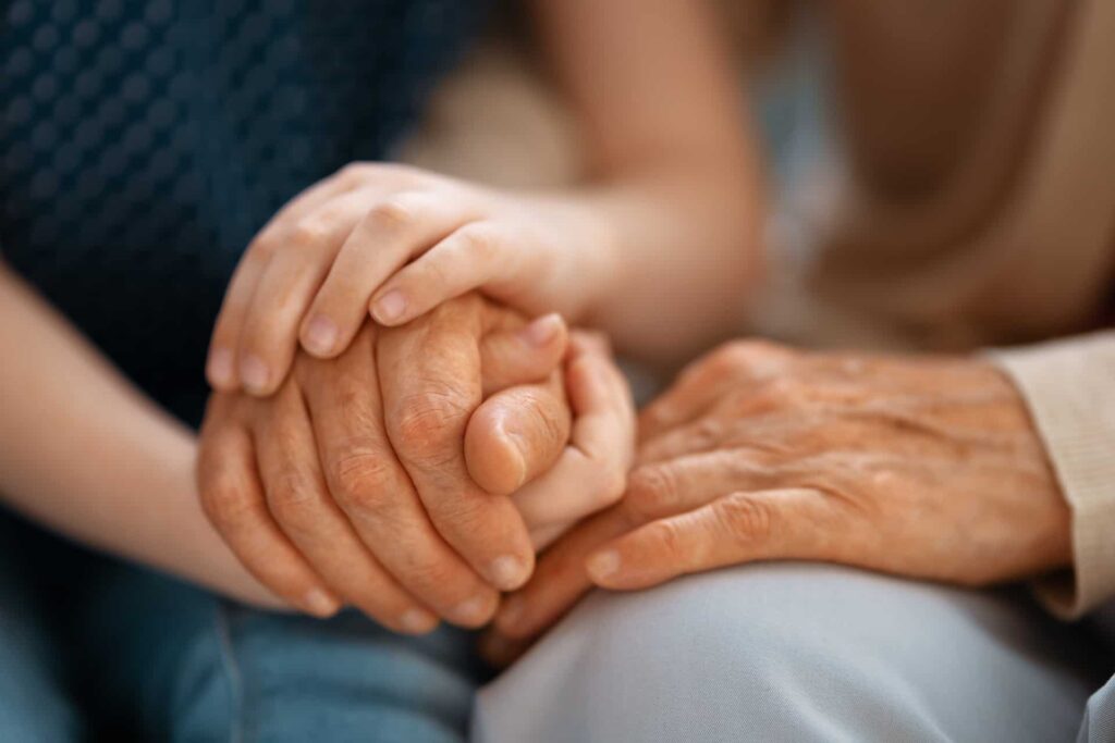 A close-up image of two people holding hands, with younger hands gently clasping older hands, symbolizing support and connection across generations, reminiscent of the trust and responsibility an executor of will in Singapore carries across families.